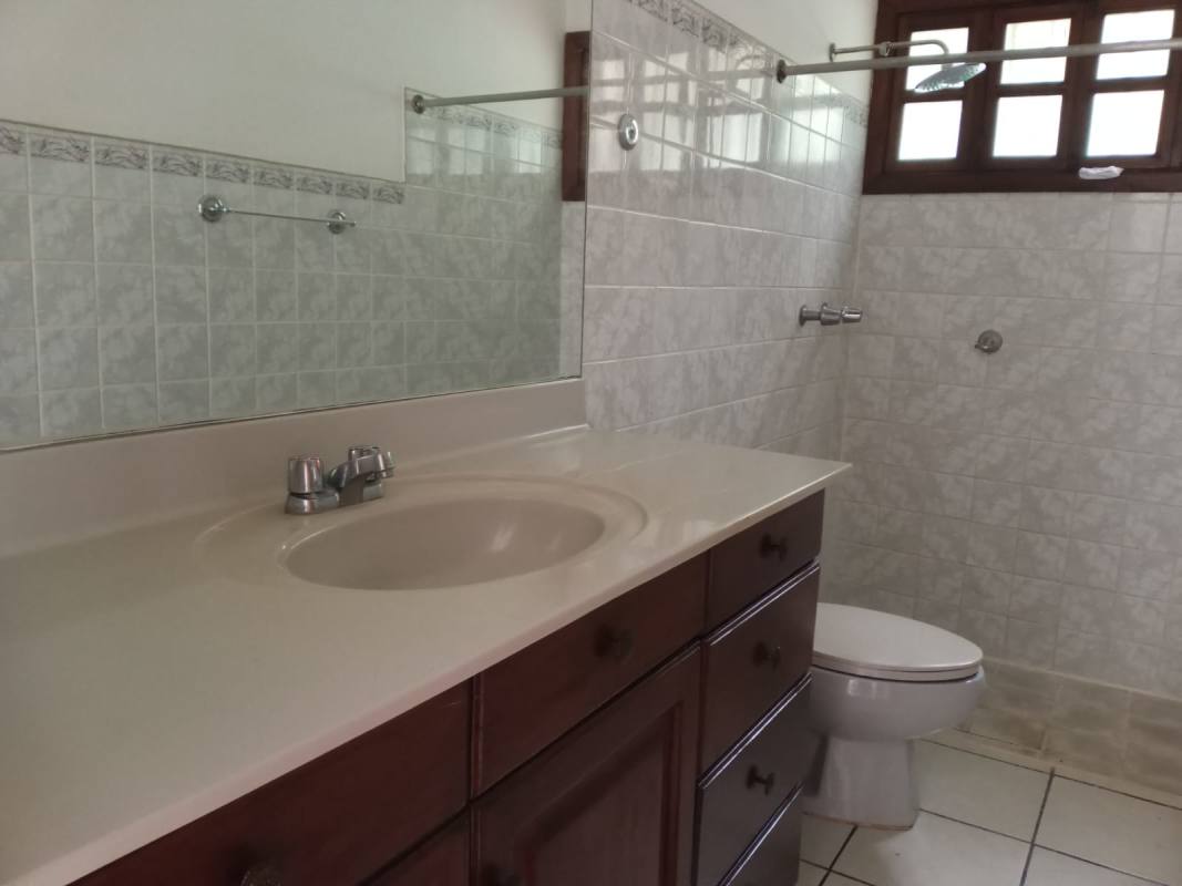 Traditional bathroom with beige ceramic tiles, wooden vanity, mirror in Santa Anita Managua house