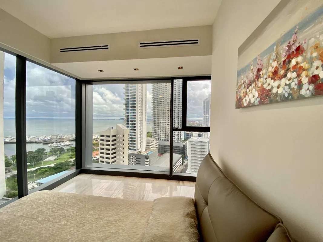 Furnished bedroom with floor-to-ceiling windows offering skyline and ocean views at PH Nuovo by Armani Casa Panama
