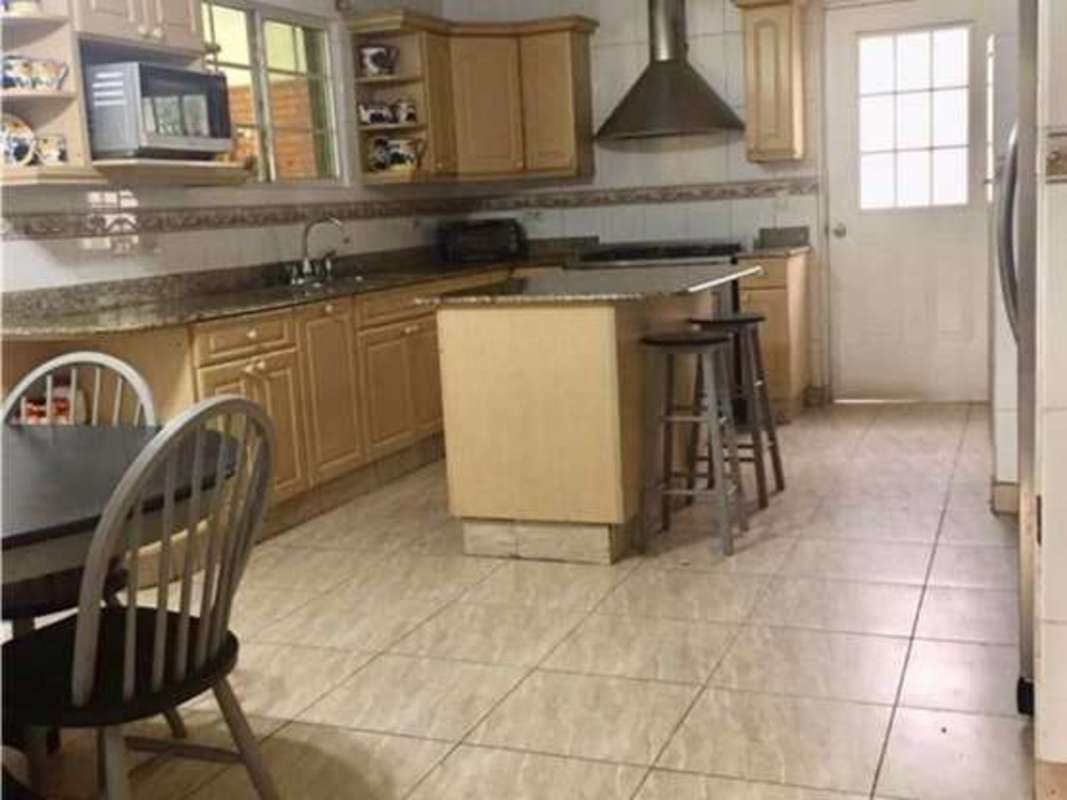 Elegant kitchen with island, wood cabinets, granite counters and appliances in PH Costa Bay Panama