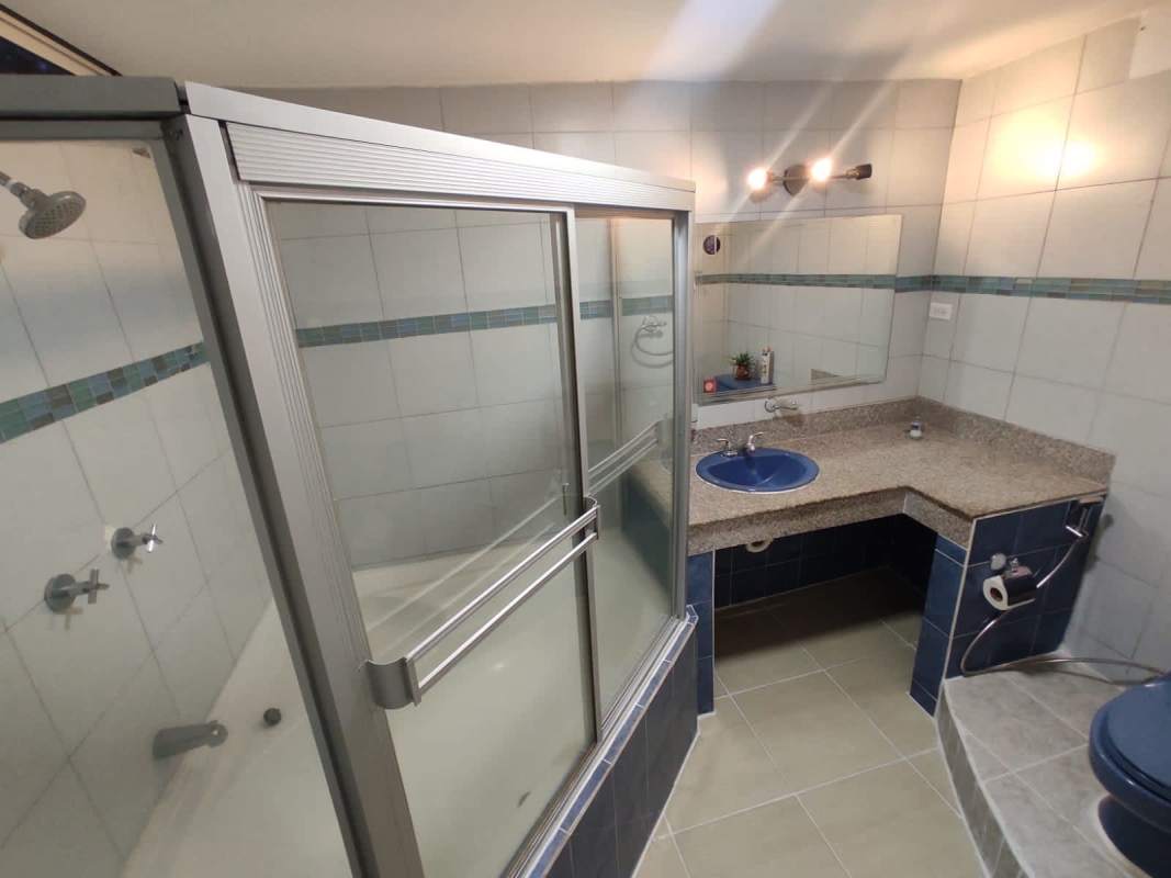 Modern bathroom with blue sink, granite countertop, glass shower enclosure in PH Cristal Park Via Argentina