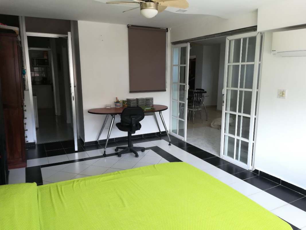 Bedroom with large window, tiled floors, green bedding PH Cristal Park El Cangrejo Panama