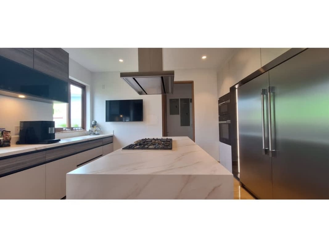 Modern kitchen featuring marble island, stainless steel appliances, and sleek cabinetry in The Woods Panama