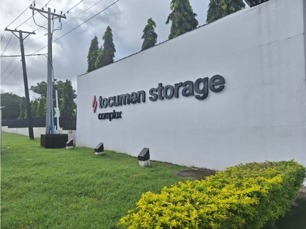Exterior entrance with Tocumen Storage Complex sign, manicured garden, and security wall