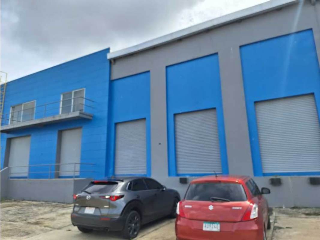 Exterior of modern industrial warehouse building with roll-up doors and parking in Pacora Panama