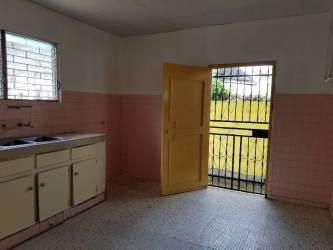 Simple kitchen with pink tile yellow door barred window Barrio Colón house for rent Panama