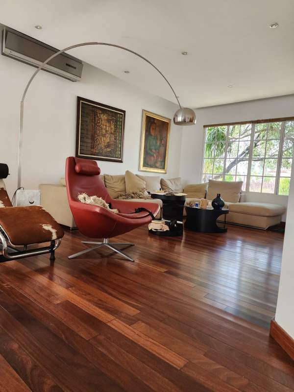 Minimalist living area with wood floor, glass doors, black chair Costa del Este