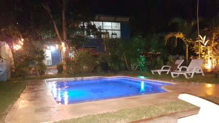 Night view illuminated swimming pool with lush tropical garden at Las Lajas beach rental Coronado