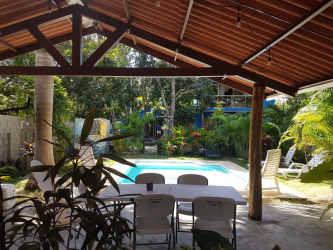 Private swimming pool with covered patio and tropical plants at Las Lajas beach house rental
