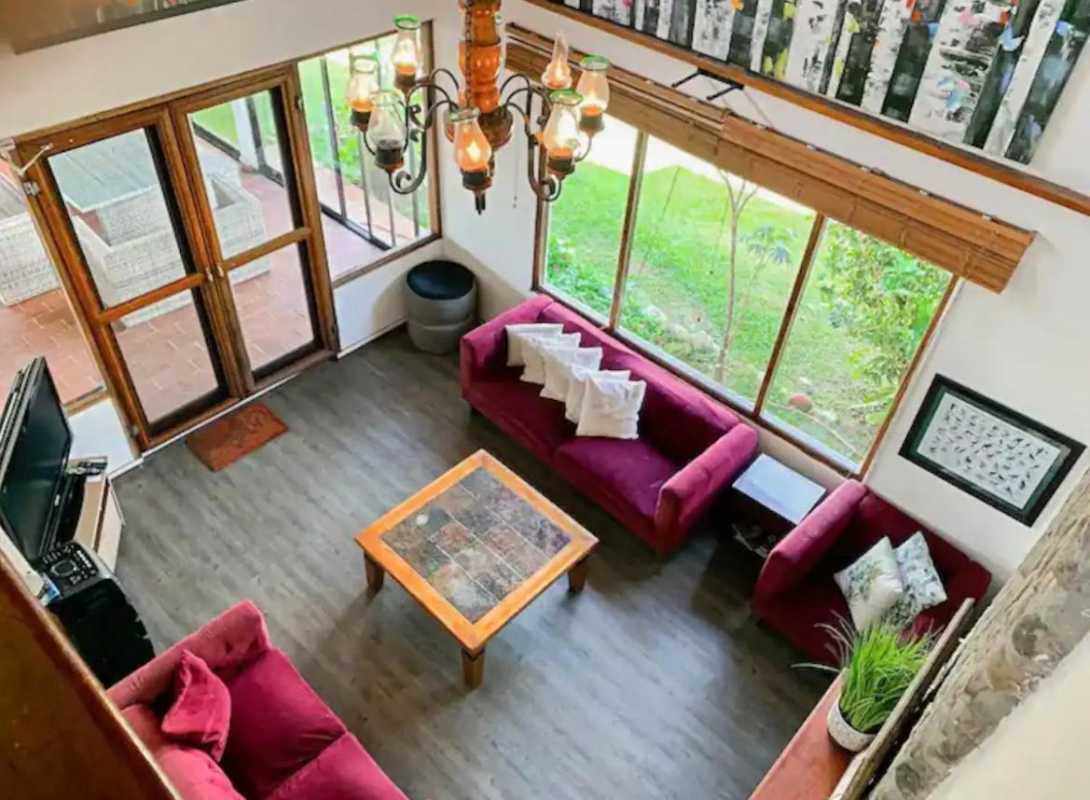 Bright enclosed sunroom with wicker furniture overlooking greenery in Cerro Azul home