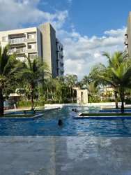 Outdoor swimming pool surrounded by palm trees lounge areas at River Valley residences Panama Pacifico