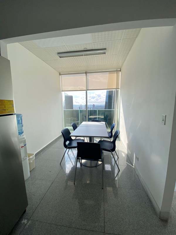 Small kitchen and dining area with city views, white table and black chairs inside F&F Tower Panama