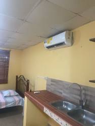 Studio apartment interior showing bed, window blinds, kitchenette, split AC Santiago Panama