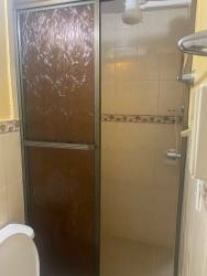 Bathroom featuring pedestal sink, frosted glass shower doors, beige tiles in Santiago studio rental