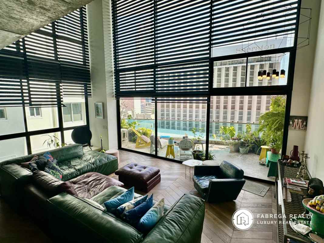 Modern living room with floor-to-ceiling windows, terrace access, city and partial ocean views in Premier Loft Panama