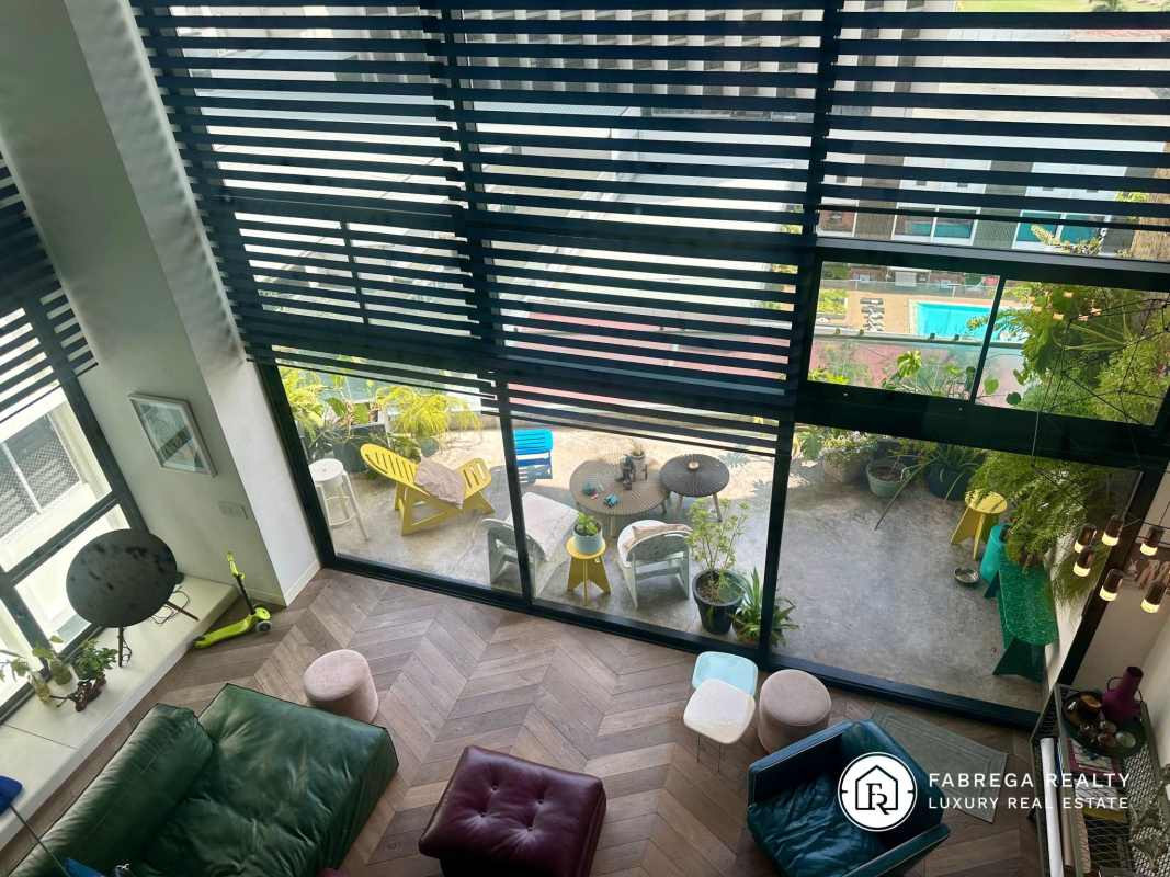 Modern loft double-height windows with garden and pool views Premier Loft Panama