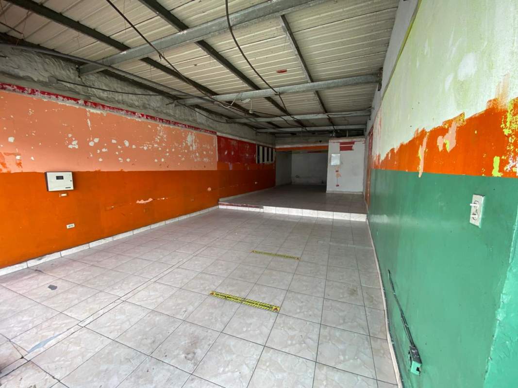 Empty painted commercial interior with tiled floor and exposed ceiling beams Pedregal Panama