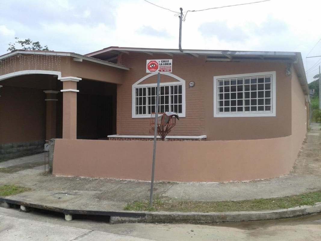 Tan house with white barred windows, arched driveway carport on corner lot in Villa Zaita Panama