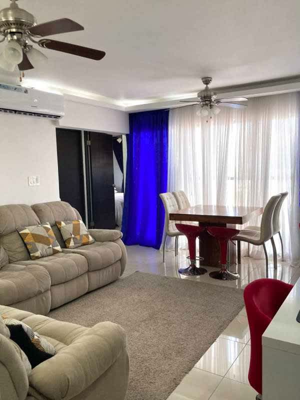 Bright living dining room with beige sofas, blue curtains, open layout in PH Centennial Panama