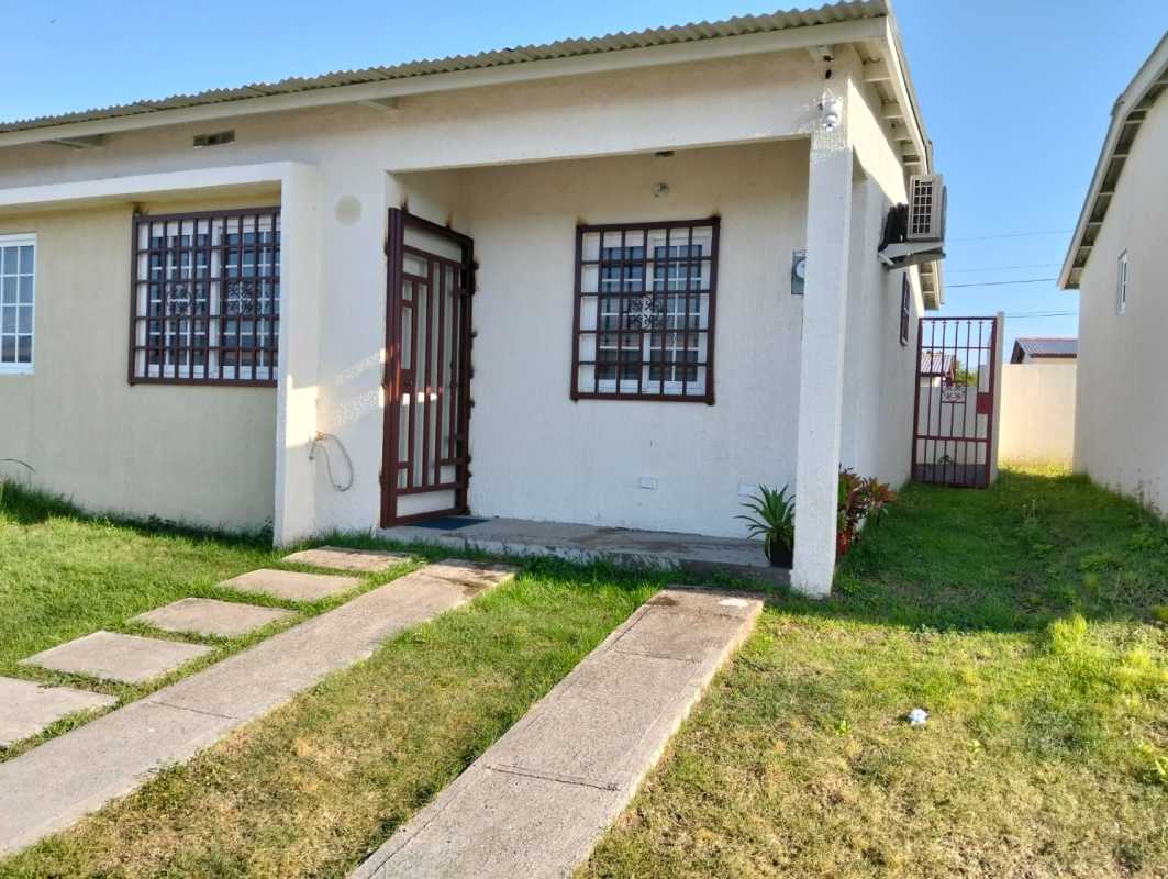 Front exterior view with iron security gate, white walls, and red metal gate at Altos del Azul community rental Panama