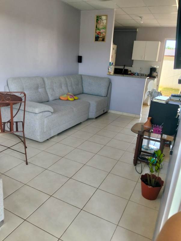 Single story rental home view with porch, window grills, lawn, gated entry Cabra Panama
