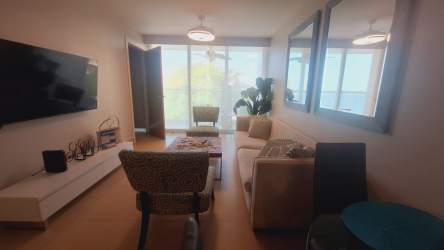 Balcony with glass railing overlooking ocean, swimming pools and palm trees in Bahia Resort Nueva Gorgona Panama