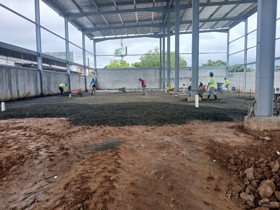 Construction workers pouring concrete slab inside steel framed warehouse in Panama