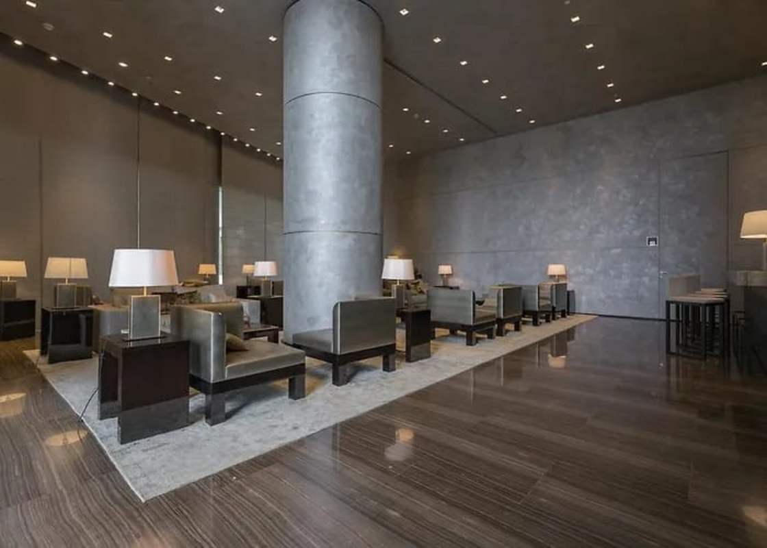Minimalist lobby area with marble floors, cylindrical pillars and modern seating at Nuovo by Armani Casa
