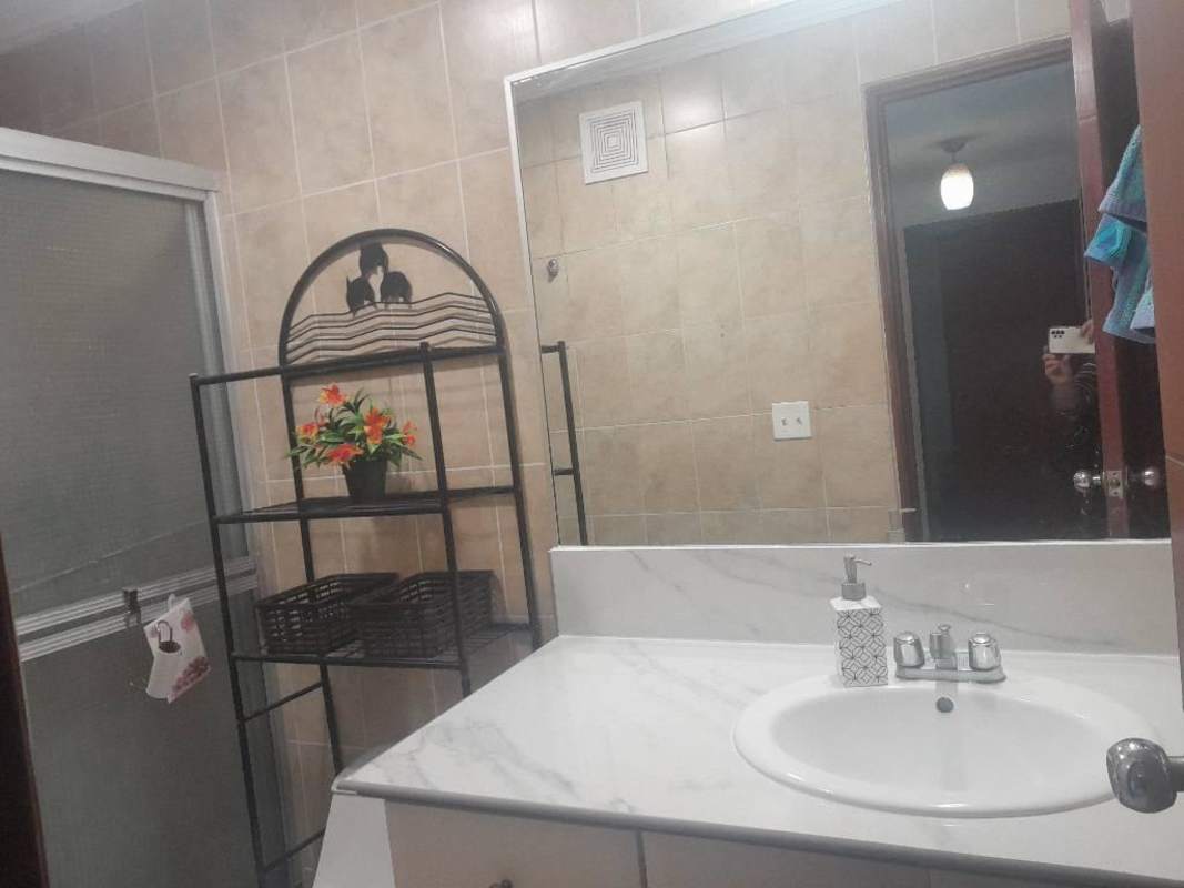 Tiled bathroom with shower enclosure, hot water, mirror and storage at PH El Dorado Panama