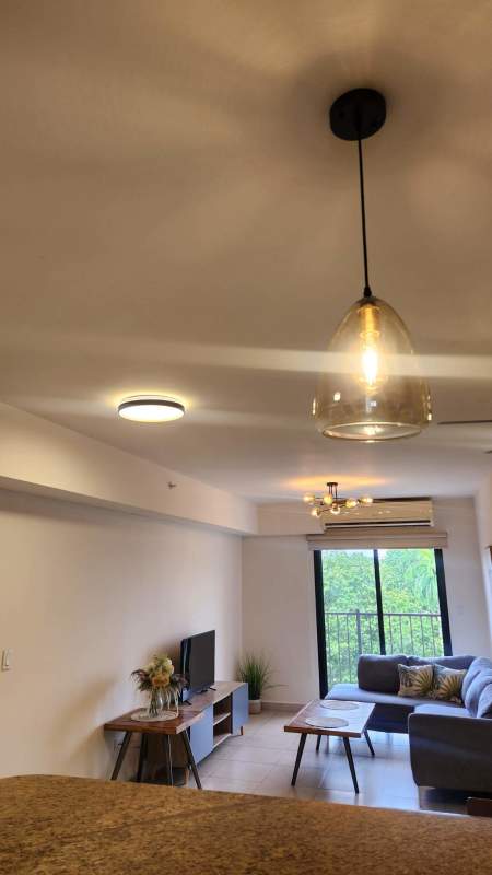 Bright furnished living room with balcony access and garden views Embassy Club Clayton Panama City