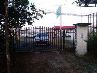 Wide garden and parking space viewed through gate for commercial use Santiago Panama