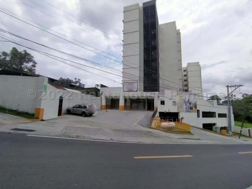 Multi-story mixed residential commercial tower with parking on a sloped urban street Panama City