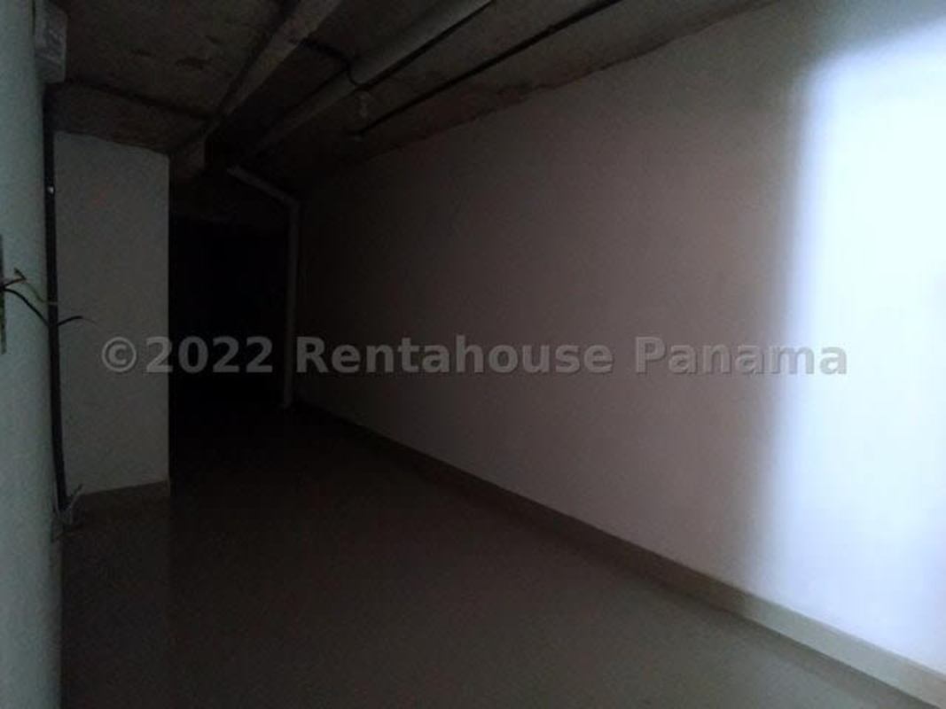 Dimly lit access corridor in mixed-use building with visible pipes - Panama City