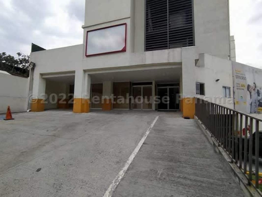Modern commercial building with parking ramp and covered spaces in busy urban Panama City area