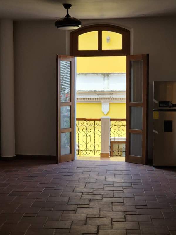 Living room with arched window door, terracotta flooring, and ceiling fan in Casco Viejo apartment