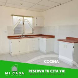 Simple white kitchen with wood countertop, cabinets and window with bars