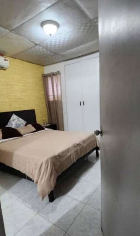 Bedroom with patterned accent wall, wood bed, dresser and tile floors in San Antonio Panama