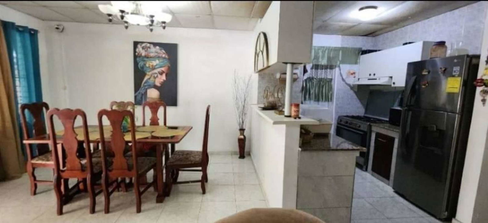 Dining area with wooden dining table, hanging chandelier, adjacent kitchen appliances in El Valle San Antonio Panama