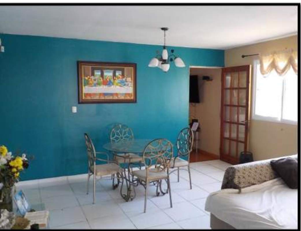 Dining area with teal accent wall and glass-top table in Altos de La Castellana Panama City