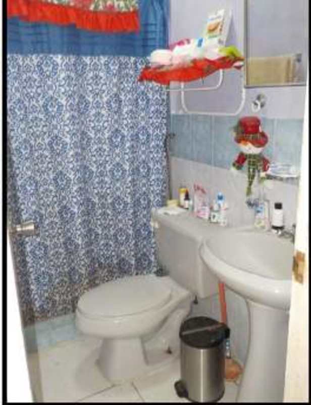 Compact bathroom with blue and white shower curtain pedestal sink in Panama City