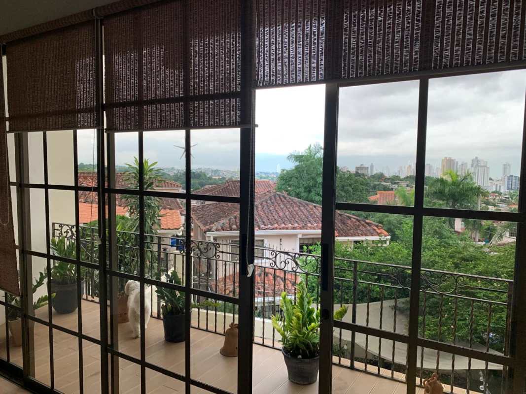 Tiled staircase with decorative metal railing leading to entryway with glass door in Altos de Bethania Panama City home