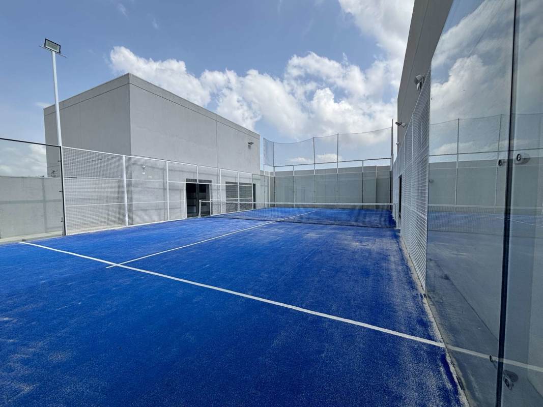 Blue rooftop padel tennis court enclosed with glass walls at Ocean House Santa Maria Panama City