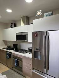 Modern kitchen with gas cooktop white cabinetry stainless refrigerator Buenaventura