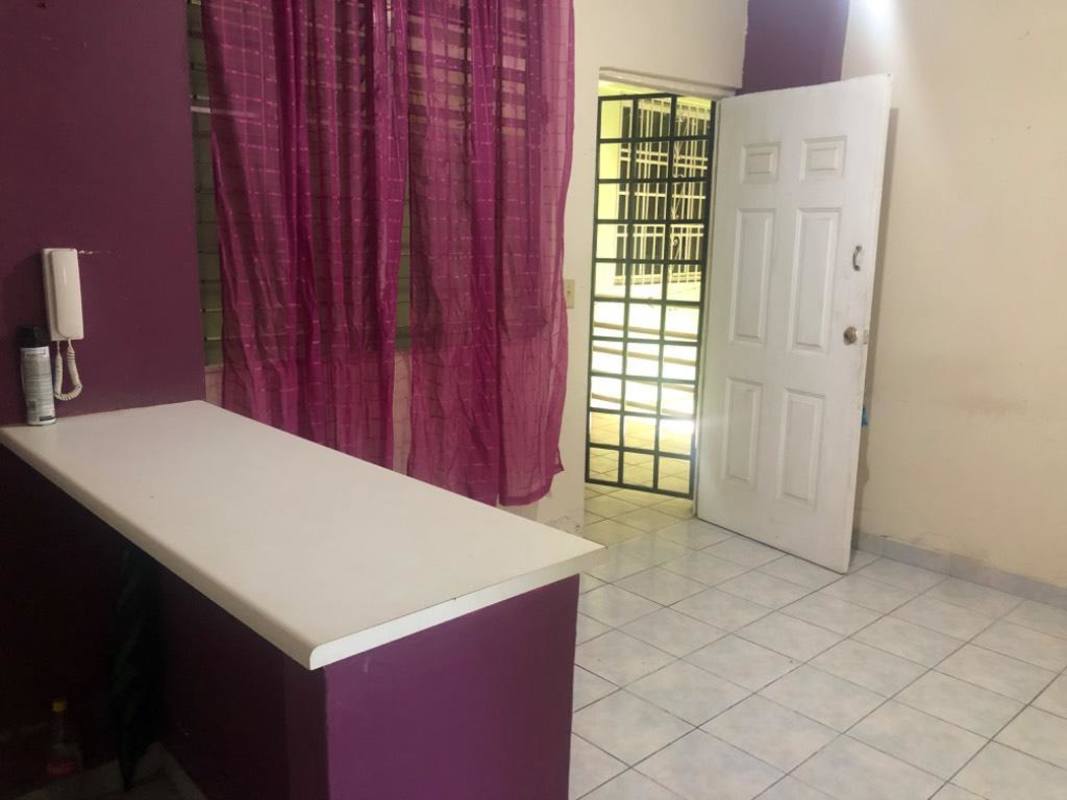 Living entry area in affordable studio with purple accent wall and white door Parque Lefevre Panama