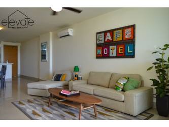 Living room with sectional sofa, wall art, AC, ceiling fan in beach apartment Casamar Panama