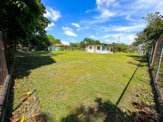 Large flat grassy lot for sale in Rio Mar, Panama, partially fenced with surrounding green areas near oceanfront