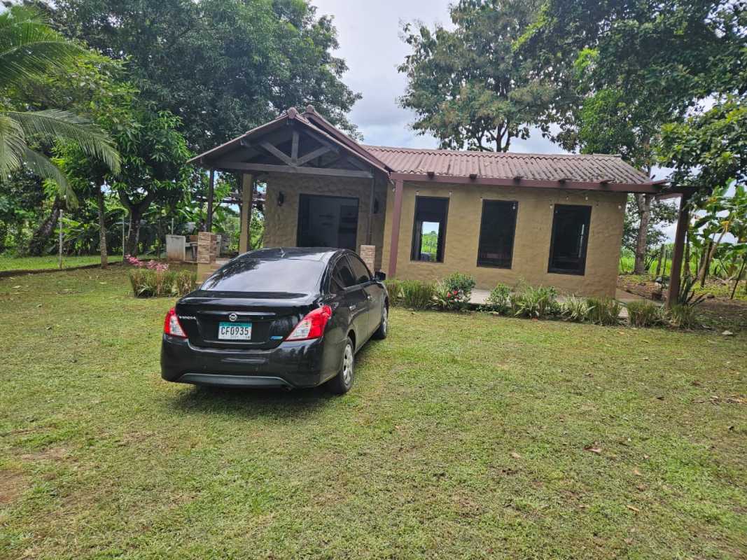 Single story house with fenced garden and cars parked in tropical setting Pacora Panama