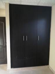 Modern bedroom with large black built-in wardrobe in rental house Playa Leona La Mitra