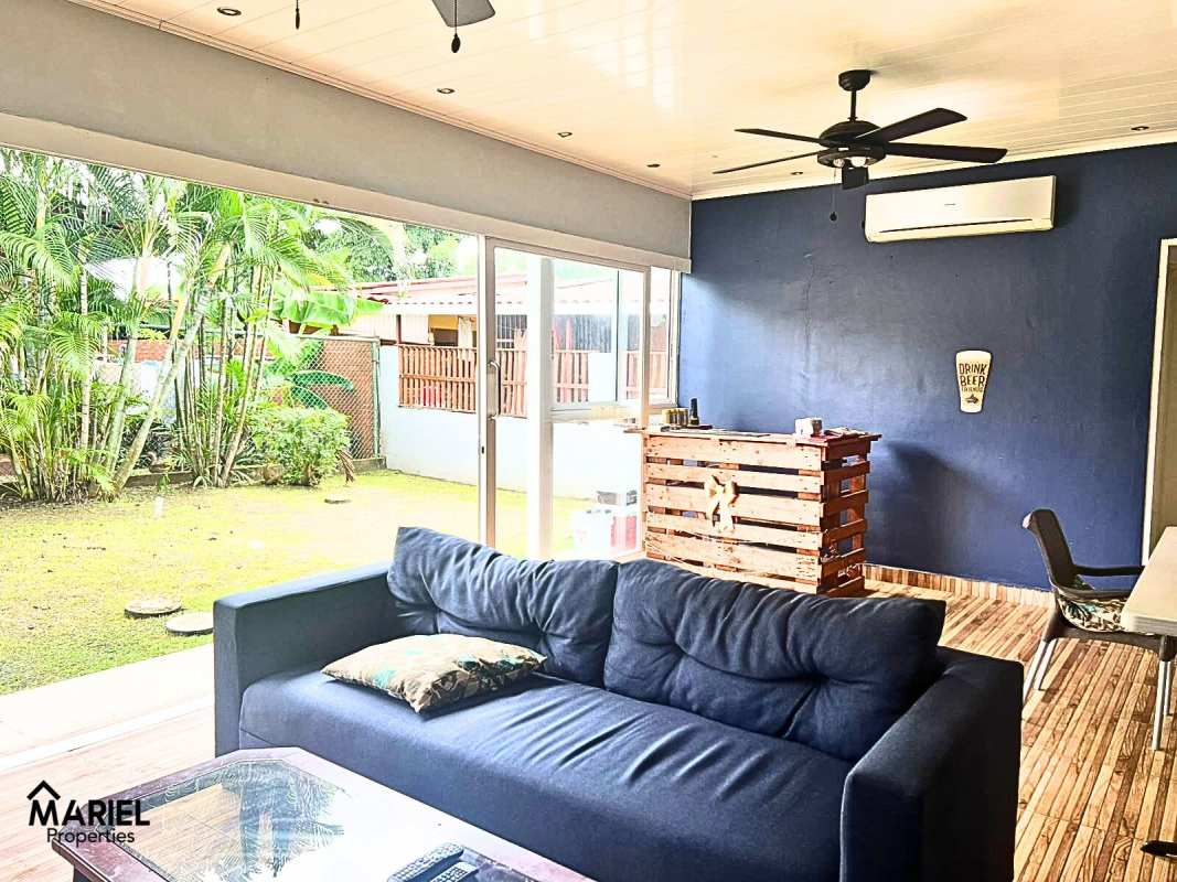 Living room with blue sofa and sliding doors to green yard in Panama