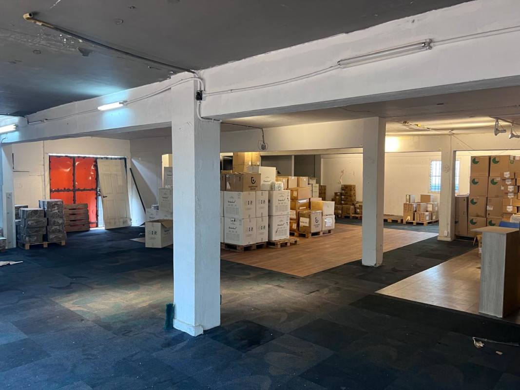 Warehouse with large barred windows, mixed flooring, stacked boxes in Calidonia Panama City for rent