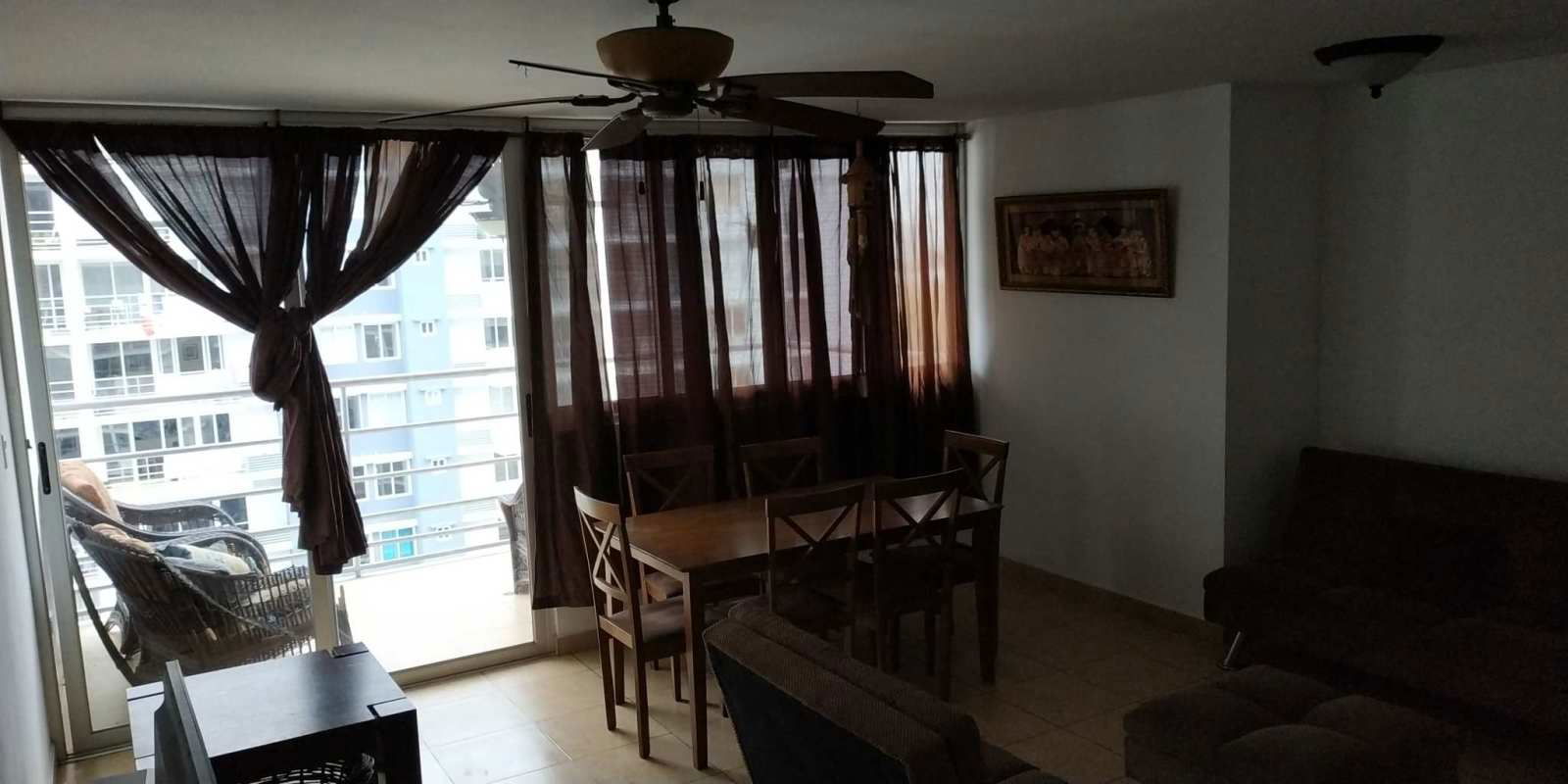Open living dining room with brown curtains, balcony access, PH Transistmica Panama